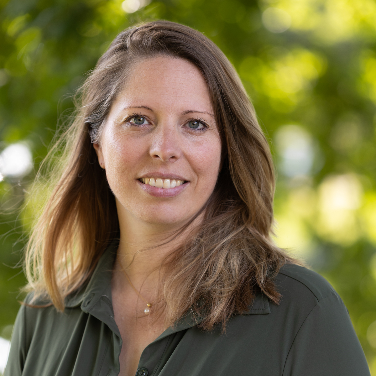 herapeut Lieke Helmes is met hoofd en schouders te zien, met groene bladeren op de achtergrond